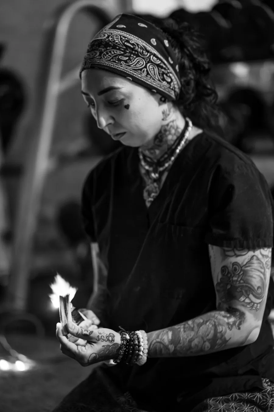 Brittney Noelle in scrubs holding lit palo santo before a session — black-and-white portrait