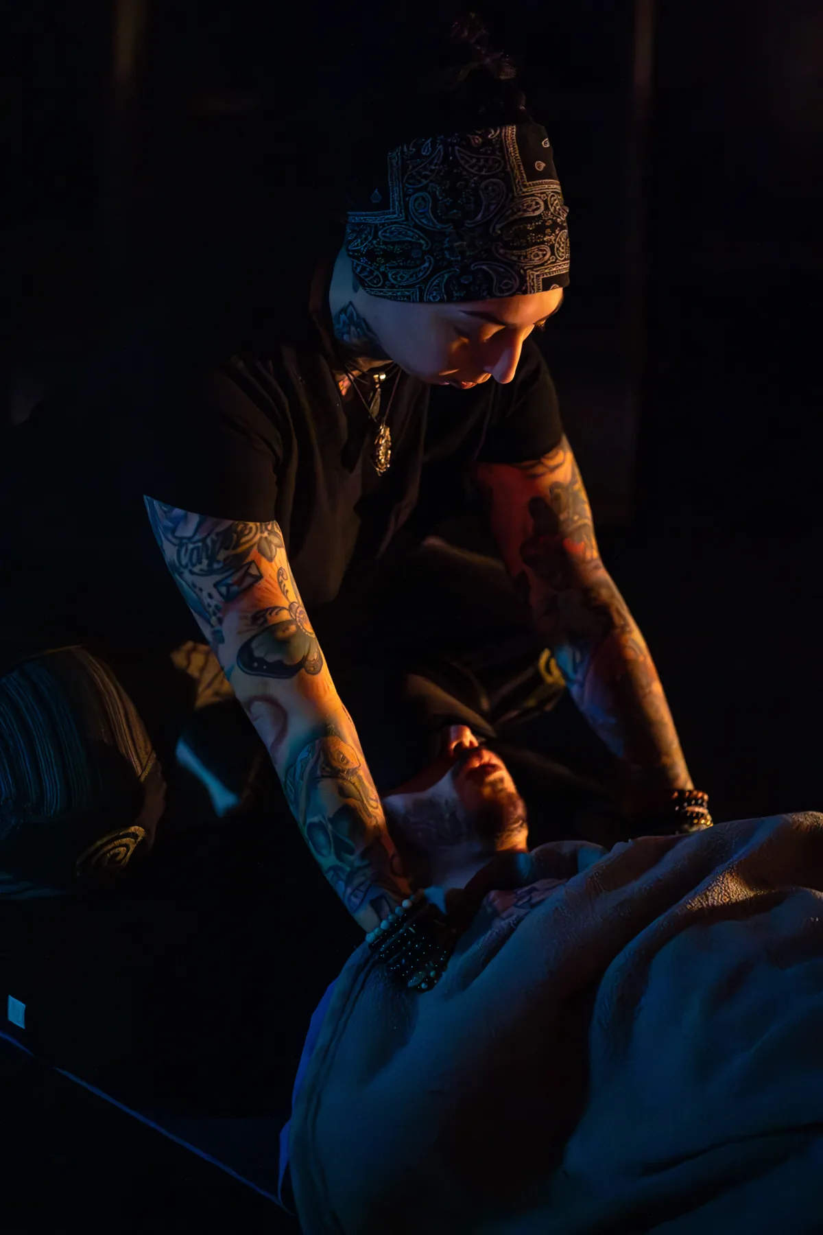 Brittney Noelle performing hands-on bodywork on a client in dramatic low light